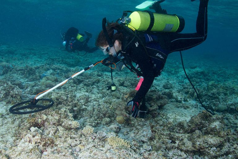 A diver surveying with a handheld magnetometer