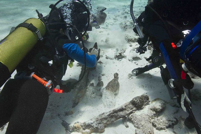 Divers investigating partially exposed artefacts