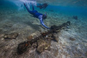Maritime archaeologist Peter Illidge investigates a windlass component on the reef top. Image: Julia Sumerling for Silentworld Foundation, 2017.